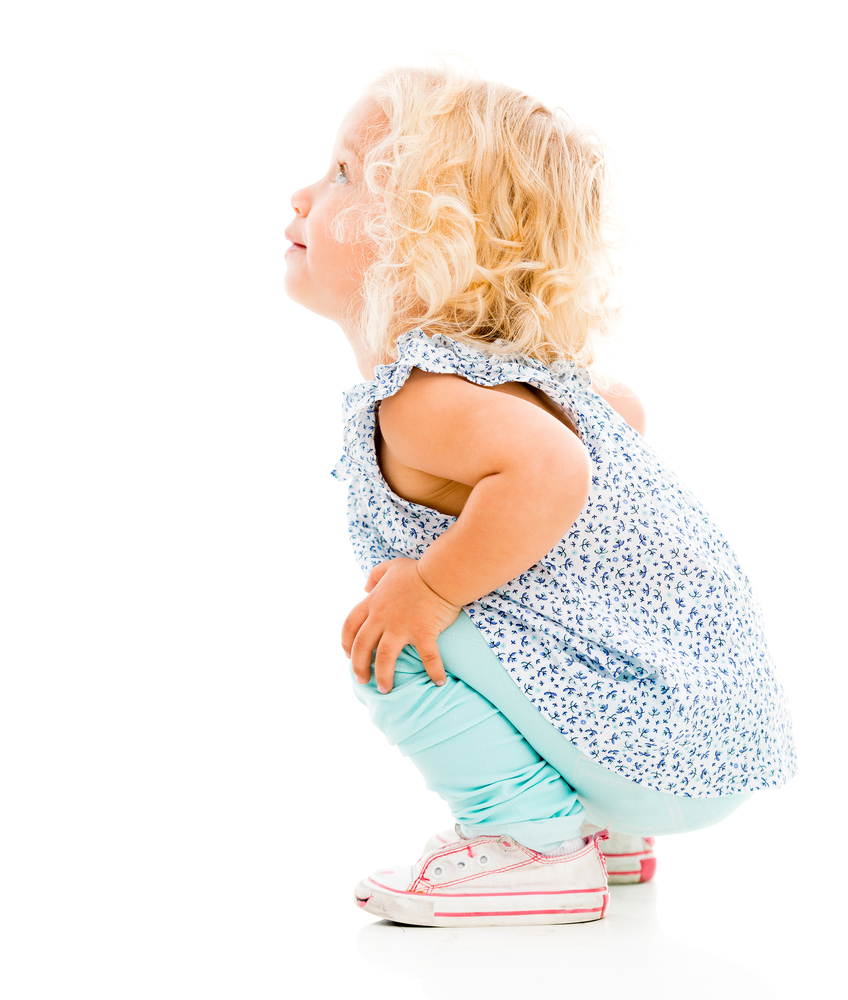 Little girl squatting down and looking up - isolated over white background